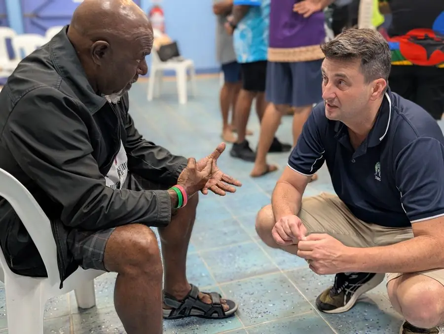 John Palmer kneeling to talk with a community member during a consultation
